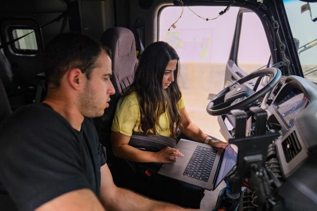 Two Stack AV employees collaboratively working on a laptop in a truck